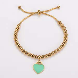 Detailansicht eines goldenen Edelstahl-Perlenarmbands mit einem grünen Herzanhänger.