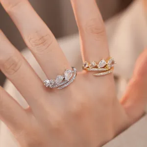 Detailopname van elegante open ringen met druppelvormige zirkoon in zilver en goud aan de vingers