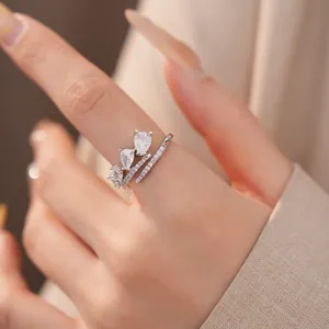 Close-up detail van een elegante zilveren open ring met zirkoon waterdruppel aan vinger.
