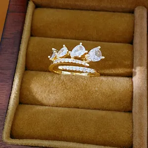 Close-up van een elegante gouden open ring met drie sprankelende peer-vormige zirkoon