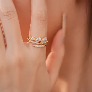 Close-up van een elegante gouden open ring met peervormige zirkonia en pavé diamanten.