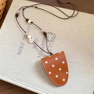 Close-up of a brown polka dot leather magnetic glasses clip on a textured book surface.