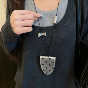 Detail view of a polka dot leather magnetic eyeglass holder necklace worn on a sweater.