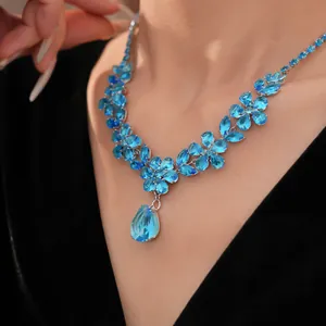 Primo piano di una collana a fiori in zircone blu con ciondolo a goccia su modella