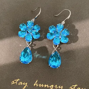 Dettaglio degli eleganti orecchini in zircone blu con design a fiore e a goccia