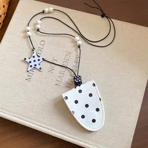 Close-up of a white polka dot leather glasses holder necklace with star charm on a book