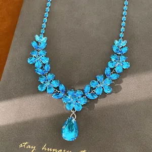 Visuale dettagliata dell'elegante collana con fiori in zircone blu e pendente a goccia.
