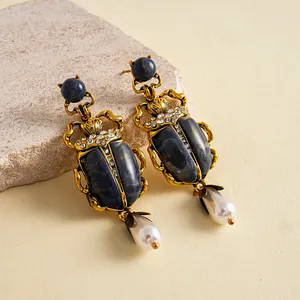 Vue détaillée des boucles d'oreilles scarabée vintage avec pierre bleue et perle