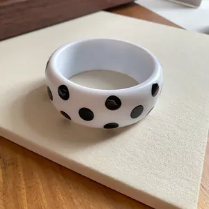 Nahaufnahme eines weißen Y2K-Resin-Armreifs mit markantem schwarzen Punktmuster-Design