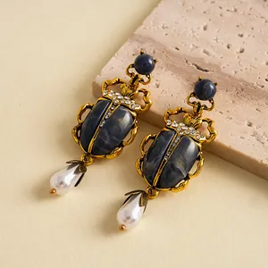Détail des boucles d'oreilles scarabée vintage avec strass et perles gouttes
