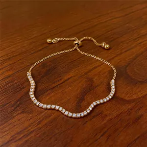 Nahaufnahme eines goldfarbenen, verstellbaren Armbands mit glitzernden Steinen auf Holz