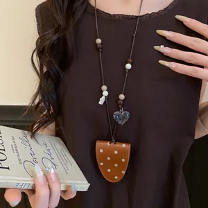 Detail view of a polka-dot leather magnetic eyeglass holder necklace on a model's outfit