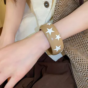 Detailansicht eines Y2K-Retro-Resin-Armreifs mit weißem Sternenmuster auf khakifarbenem Grund