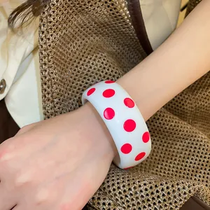 Detaillierte Nahaufnahme eines weißen Y2K-Resin-Armreifs mit rosa Punkten am Arm