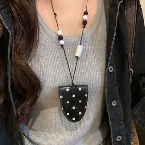 Close-up detail of a black leather magnetic sunglasses holder necklace with polka dots.