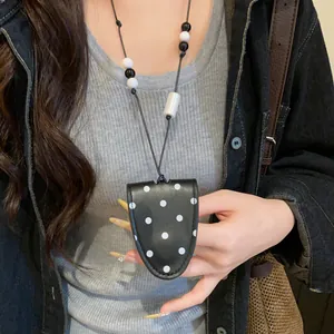 Detail of a black polka-dot leather magnetic sunglasses holder necklace on a model