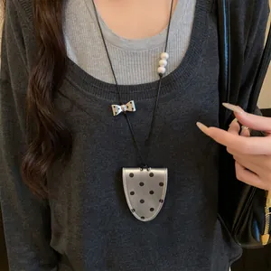 Close-up of a silver polka-dot leather magnetic glasses clip necklace worn on a sweater