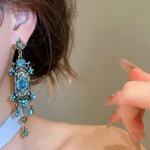 Elegante vintage lange druppeloorbellen in paleisstijl met blauwe strass op een model