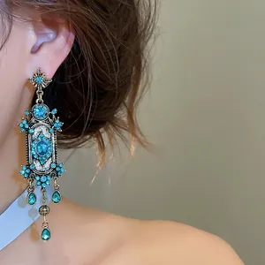 Close-up van vintage gouden oorbellen in hofstijl met blauwe strass-steentjes en hangers