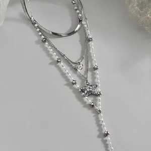 Detailed macro view of silver multi-layered pearl necklace featuring star and heart pendants