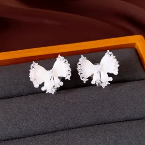 Detailaufnahme von Schleifen-Ohrclips mit Zirkon, Perlen und Emaille auf schwarzem Samt