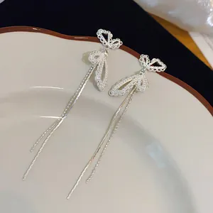 Détail rapproché des élégantes boucles d'oreilles papillon argentées avec accents perlés