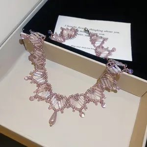 Détail d'un ensemble de bijoux fait main avec collier et bracelet en cristal rose et perles