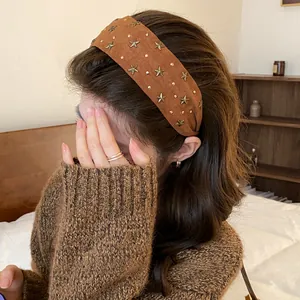 Brede bruine fluwelen haarband met gouden sterren gedragen door een model in een kamer