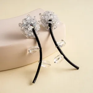 Détail des boucles d'oreilles fleurs avec perles de verre et tige en cuir noir élégante.