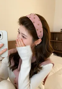 Close-up van een modieuze roze brede hoofdband met gouden sterren bij een jonge Aziatische vrouw