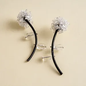 Détail macro de boucles d'oreilles florales avec tiges en cuir noir et cristaux brillants