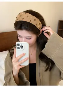 Brede beige hoofdband met metalen sterren gedragen door vrouw in een spiegel selfie