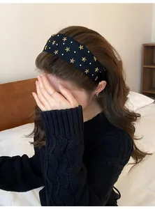 Detailopname van zwarte haarband met gouden sterren en parels