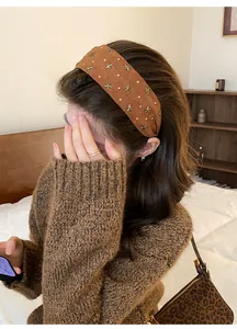 Bruine brede hoofdband met sterstuds gedragen door een vrouw in lifestyle.