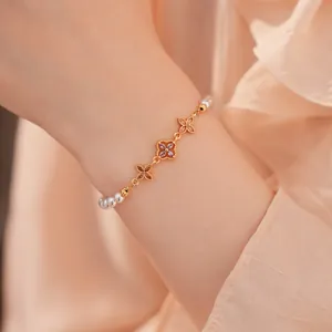 Detailopname van 18K vergulde bloemenarmband met paarse zirkonia en parels