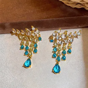Detailed macro view of gold-plated water-drop tassel earrings with gradient blue zircons