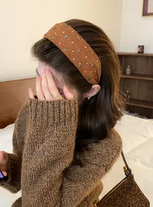 Gedetailleerd zijaanzicht van een bruine brede haarband met metalen sterren op een model