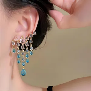 Detailed close-up shot of elegant blue and clear zircon teardrop tassel earrings worn by a model