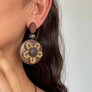 Nahaufnahme eines ethnischen Strohblumen-Ohrrings mit dunkler Holzbasis an einem Model