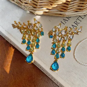Close-up of elegant gold tassel earrings with blue and clear zircon teardrops.