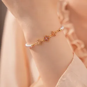 Detailweergave van een elegante 18K vergulde zirkoonbloem- en parelarmband