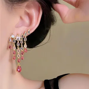 Close-up of elegant teardrop tassel earrings with sparkling pink zirconia stones.