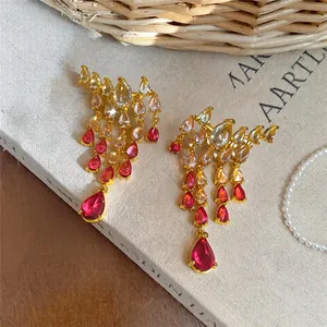 Close-up of elegant gold tassel earrings with red and clear pear-cut zirconia