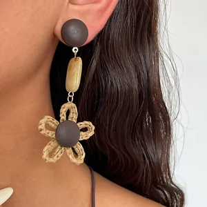 Makrodetail eines ethnischen Ohrrings mit geflochtener Blume und Harzakzenten für Damen