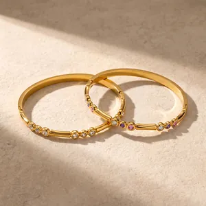 Nahaufnahme von goldenen Edelstahlarmreifen mit bunten Zirkonsteinen im Detail