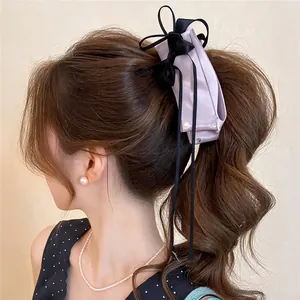 Detailed side view of a purple fabric bow hair clip on a model's ponytail