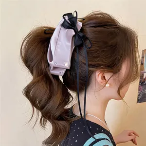 Elegant lilac fabric bow hair clip with black ribbon and pearl detail on ponytail
