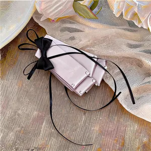 Detailed view of an elegant pink satin bow hair clip with black ribbon and rhinestones