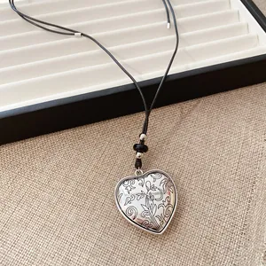Gros plan d'un pendentif en forme de cœur gravé sur un cordon en cuir noir épuré