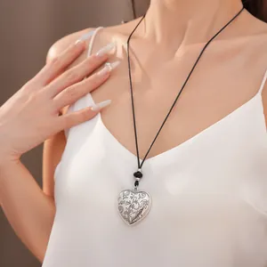 Détail d'un collier avec pendentif cœur gravé sur un cordon noir porté par un mannequin
